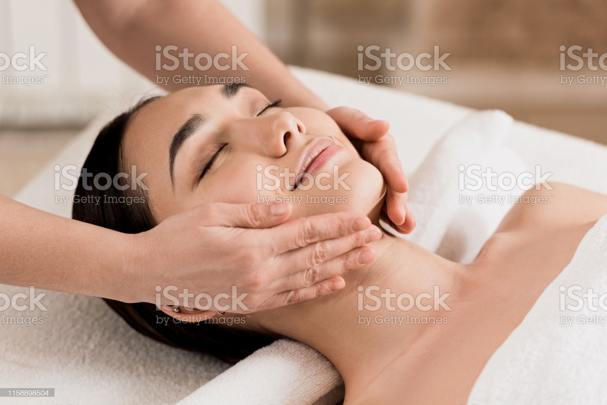 woman getting face massage with closed eyes at spa